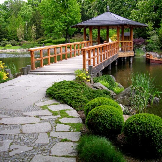 Asiatischer Park - klassisch asiatischer Steg mit Pavillion aus Holz in einem Steingarten mit Teich