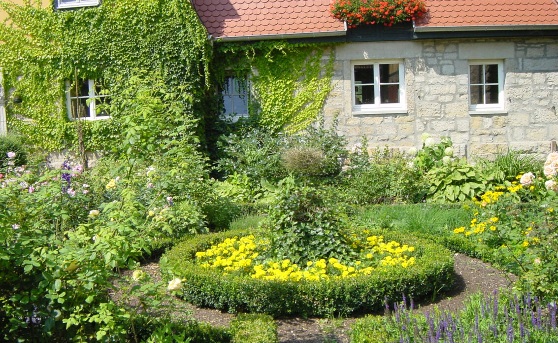 Rustikale Gartenidee – Garten eines Landhauses mit vielen Blumen als...