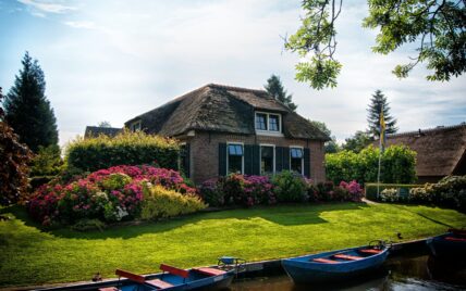 Wunderschöner niederländischer Vorgarten mit Blumen und Hecken direkt an den Grachten ge...