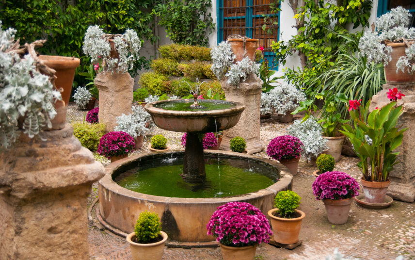 Idee für den Innenhof mit Brunnen aus Stein und vielen Blumen nach mediterraner Art – Blumentöpfe aus Ton