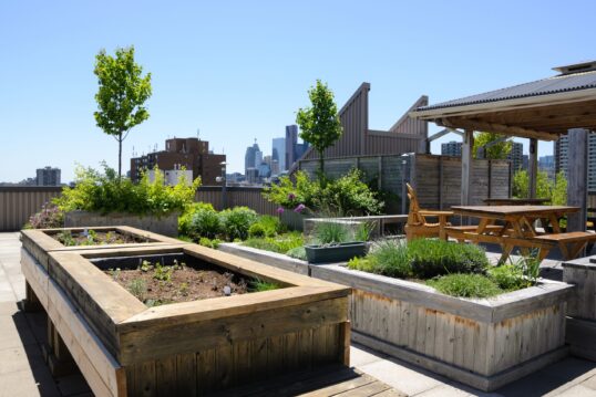 Landhaus Dachterrasse Idee – Beispiel für eine grüne Terrasse mit Hochbeeten für den Kräutergarten über den Dächern der Stadt