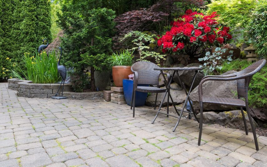 Gartenidee mit Sitzgruppe – Blumen und Gartenmöbel in Hof mit hoher Hecke als Sichtschutz