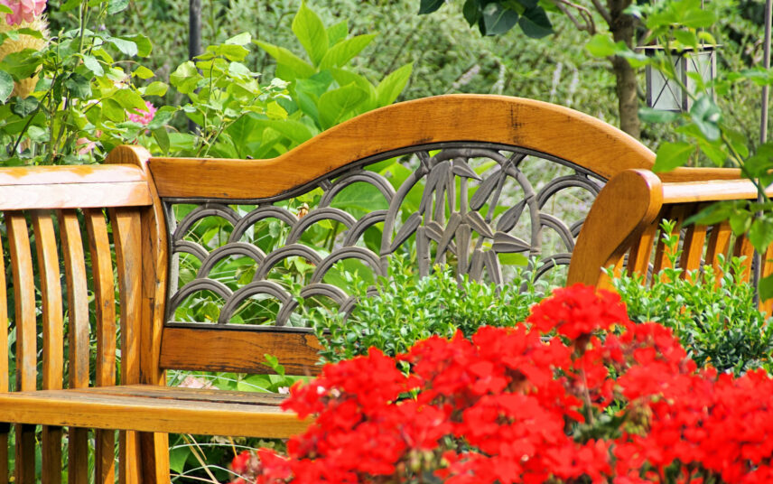 Sitzecke Idee im Garten – Dekorativ verzierter Holzbank mit Blumen davor