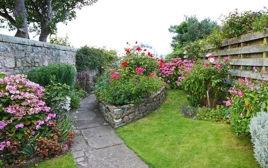 Landhaus Gartenidee – Garten mit Gartenweg aus Stein und hoher Steinmauer & Hochbeeten
