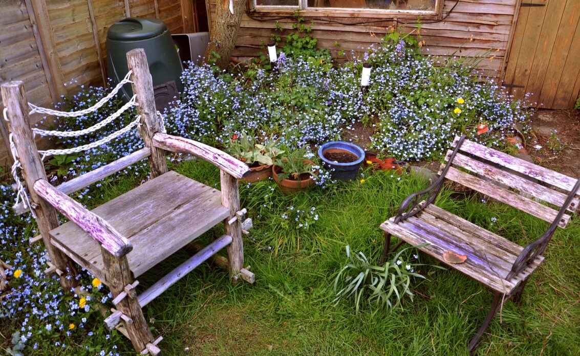 Wilder Garten mit Blumen und rustikalen Stühlen aus Holz