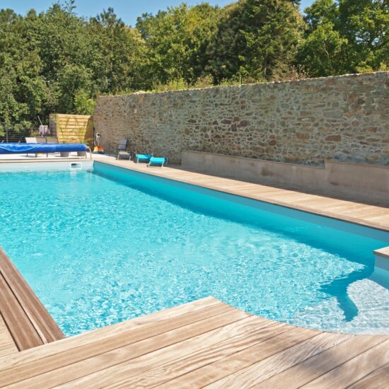 Pool im Garten Idee - Großes Schwimmbecken mit Poolumrandung aus Holz - Gartenliegen & Rattanstühle