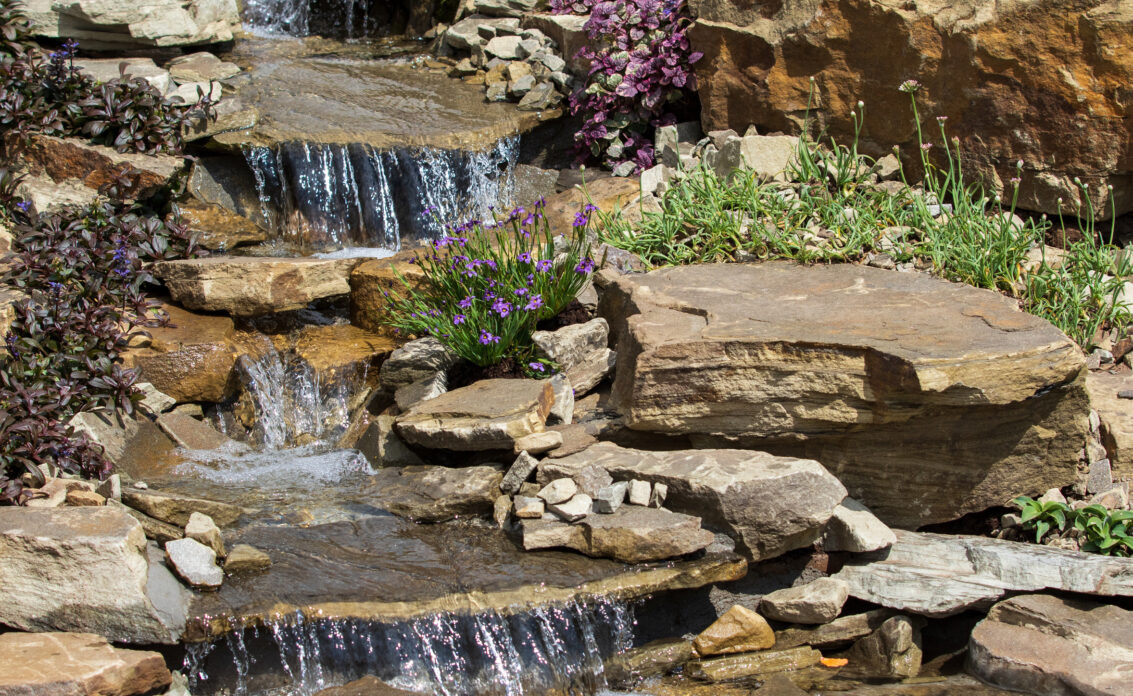 Gartengestaltung mit Wasser – Kleine Wasserfälle gestaltet mit Steinen und Blumen