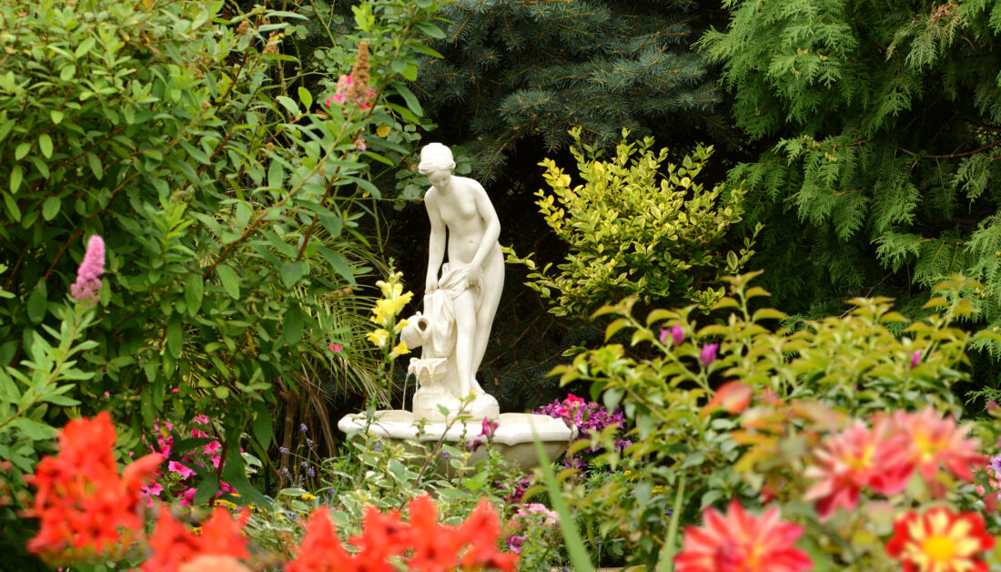 Stilvolle Gartendekoration Idee - Romantischer Garten mit kleinem Springbrunnen mit barocker Frauenskulptur & viele Gartenpflanzen