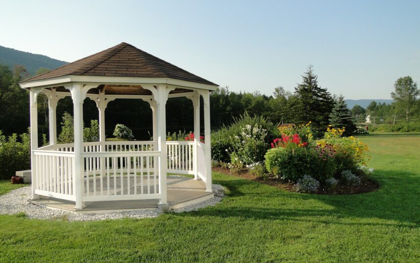 Idee für die Gartengestaltung – Kleine Terrasse mit weißem Pavillion im Landhausstil mit Kiesumrandung & großes Beet mit Gartenpflanzen