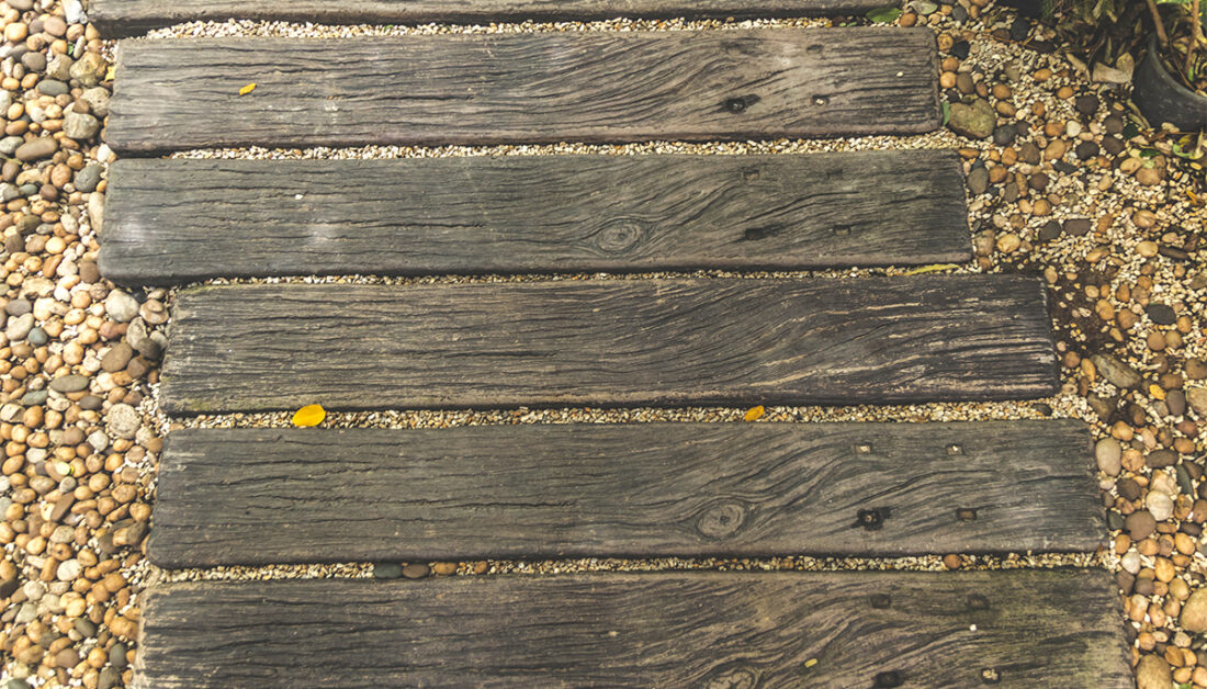 Rustikaler Gartenweg aus einzelnen Holzbohlen