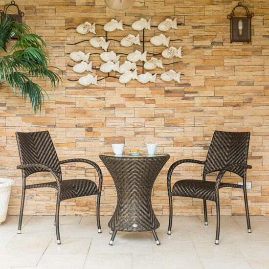 Terrasse Idee - Kleine Sitzgruppe im Rattanlook in mediterraner Umgebung mit schöner Wanddekoration und passendem Pflanzgefäß mit Palme