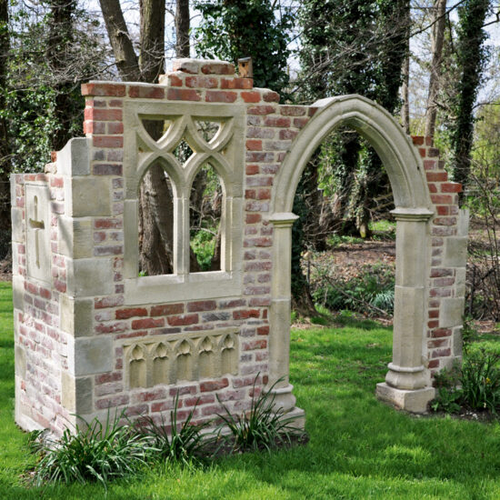 Gartengestaltung mit einer freistehenden kleinen Gartenruine auf der Wiese - Gartenruine mit gotischen Fenster und Bogen als Gartendekoration