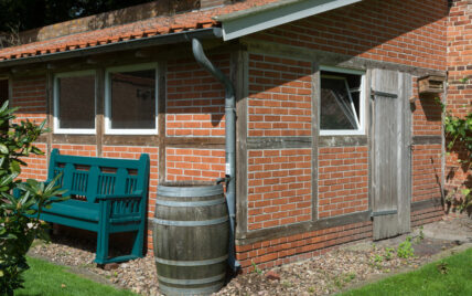 Idee für die Vorgarten- & Hauswand-Gestaltung eines Landhauses – Beispiel mit Regenfass...
