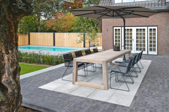Gepflasterte Landhaus Terrasse Idee mit Sitzbereich & Sonnenschutz vor dem Haus – Einbaupool Beispiel mit Holz Sichtschutz