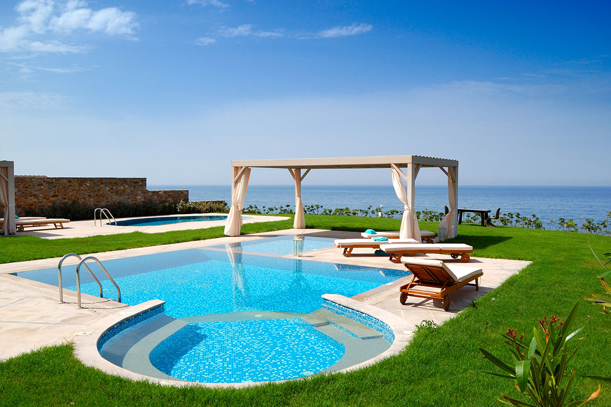 Mediterraner Poolbereich mit individueller Poolform, ergänzt mit Gartenliegen und Pavillon.