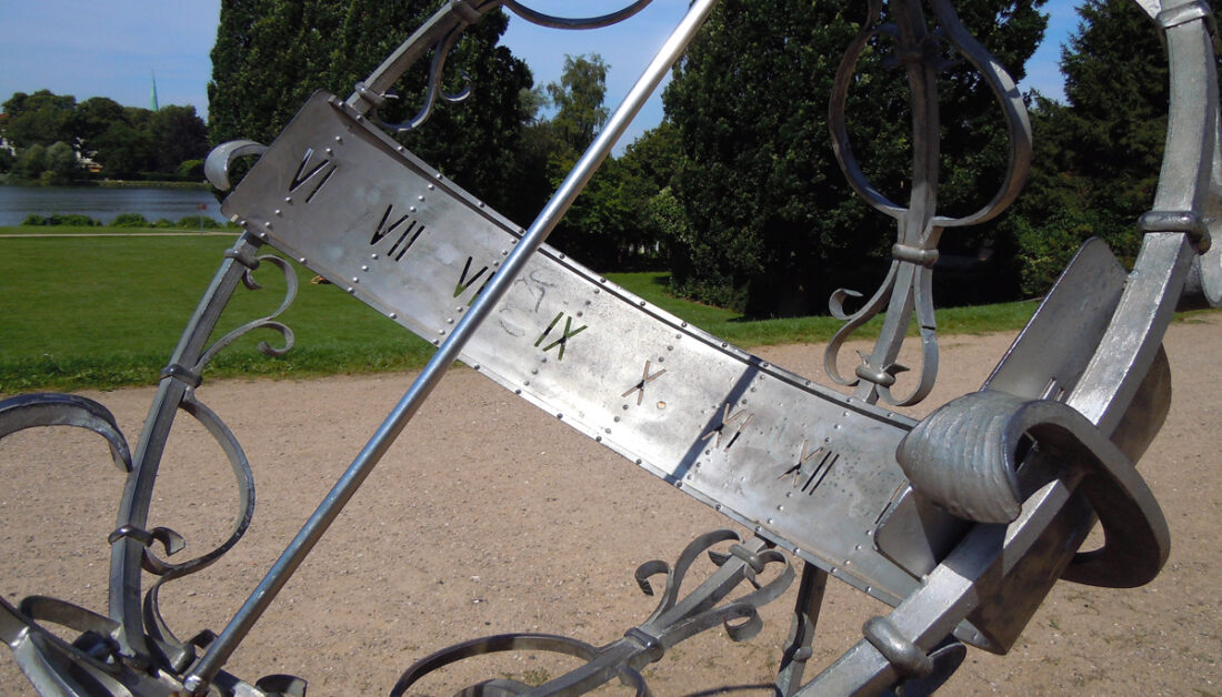 Inspiration mit Gartendekoration - Beispiel einer Metall Sonnnenuhr an einem Weg im großen Garten oder Park am See
