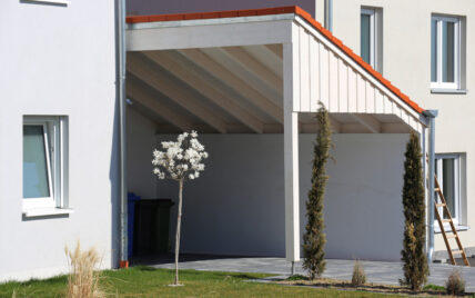 Moderner Anlehn-Carport in weiß mit roten Dachziegeln an der Hauswand als Gartenidee – ...