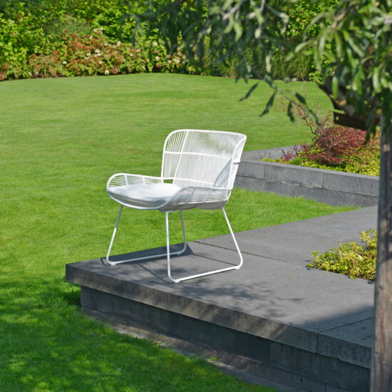 Garteninspiration - Gestaltungbeispiel mit einem Retro Stuhl auf einem breiten Beetrand - Gartenpflanzen & Heckensträucher