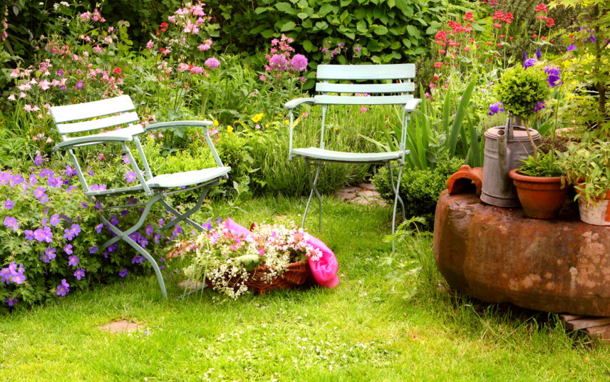 Idee für einen Wildgarten mit Gartenstühlen & Dekoration – Beispiel mit bepflanzten Blumentöpfen & Gießkanne zum bewässern des Gartens