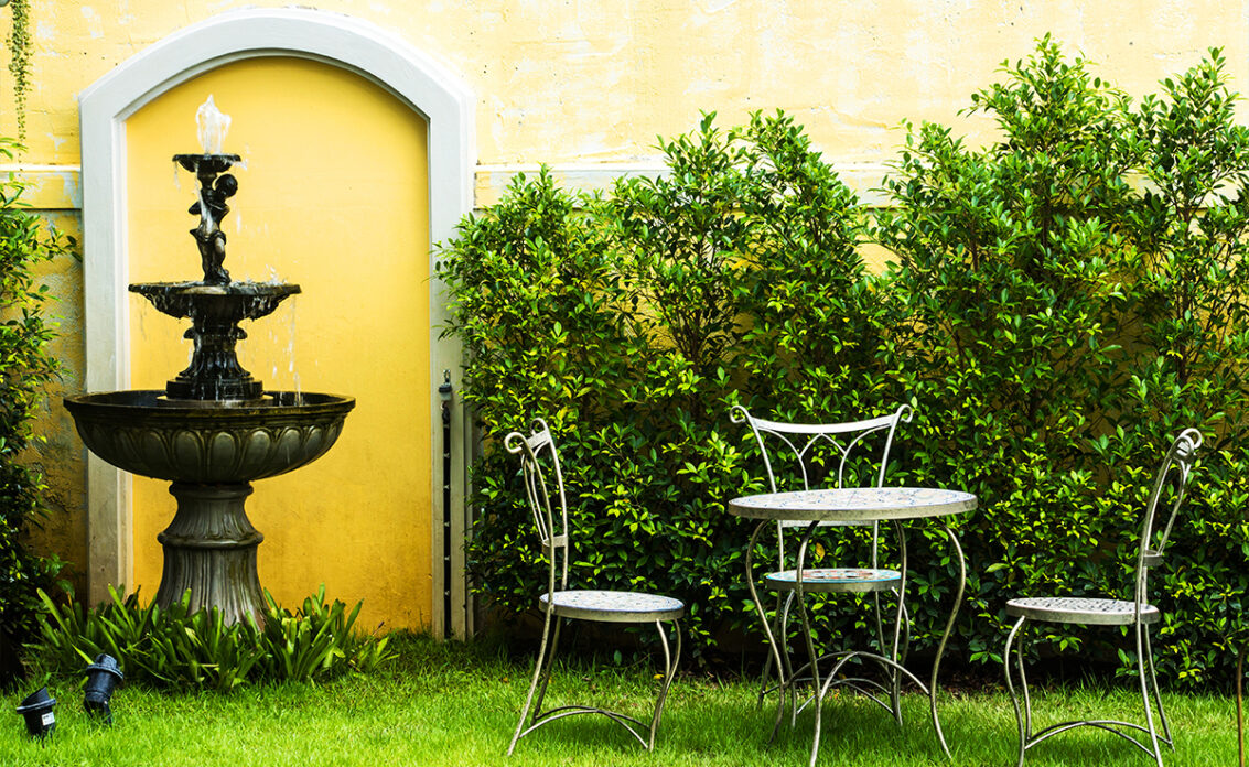 Gartenidee mit Sitzgruppe & Springbrunnen vor der Hauswand – Beispiel mit Metalltisch & ...