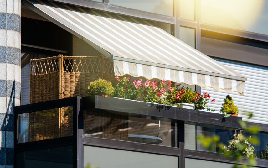 Idee für einen kleinen Balkon – Balkongestaltung mit Markise & Sichtschutzzaun – Balkongeländer mit bepflanzten Blumenkästen