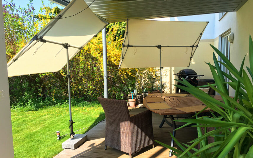 Terrassengestaltung mit freistehenden Markisen zum Kippen als Sonnenschutz – Sitzgruppe mit Rattansessel & Holztisch – Grill & Terrassenpflanzen