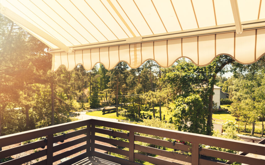Balkon Idee – Beispiel mit gestreifter Markise als Balkon Sonnenschutz – Balkongeländer aus Metall – Blick in den großen Landhausgarten