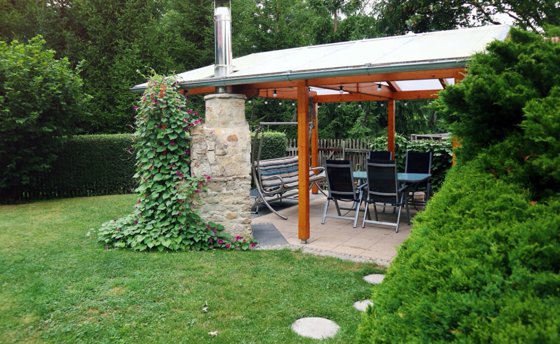Idee für eine Terrasse mit Überdachung und Sitzgruppe – Beispiel mit bepflanzten Garte...