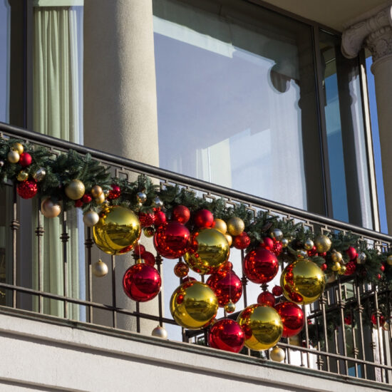 Stilvolle Idee für die Balkongestaltung mit Weihnachtsdeko - Weihnachtsgirlande mit großen & kleinen Weihnachtskugeln am Balkongeländer