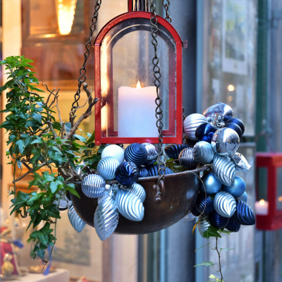 Hängende Weihnachtsdeko Idee Nachmachen - Beispiel mit dekorativer Blumenampel vor dem Fenster mit blauen Weihnachtskugeln  roter Laterne & Efeu
