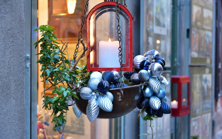 Hängende Weihnachtsdeko Idee Nachmachen – Beispiel mit dekorativer Blumenampel vor dem Fenster mit blauen Weihnachtskugeln  roter Laterne & Efeu