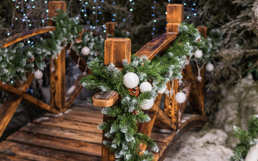 Weihnachtsdeko außen – Idee für eine geschmückte Gartenbrücke aus Holz mit einer Weihnachtsgirlande aus Tannenzweigen – Weiße Weihnachtskugeln