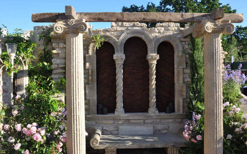 Gartendeko Idee – Element einer Gartenruine im gotischen Stil mit Säulen & Steinbank – Rosen links & rechts von der Ruine