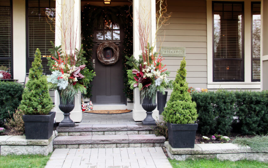 Hauseingang Gestaltung mit Weihnachtsdekoration – Beispiel mit Weihnachtsstäußen in großen Pflanzkübeln – Lichterkette um die Haustür – kleine Tannenbäume