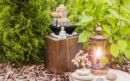 Gartendekoration im asiatischen Stil – Buddha-Skulptur & kleiner Brunnen auf einen Holzh...