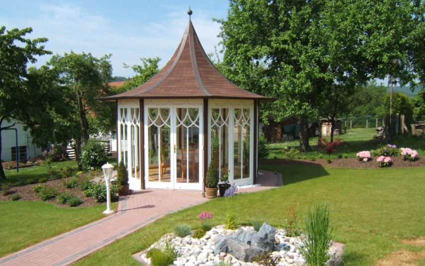 Idee für den Garten – Gartenpavillon mit spitzen Zeltdach & Sitzgruppe – Brunnen umgeben von Steinen
