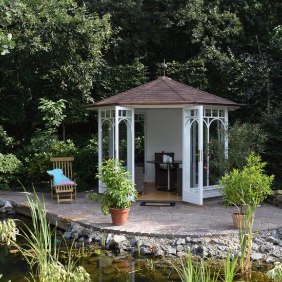 Terrasse am Gartenteich - Idee mit einem weißen Gartenpavillon & Sitzgruppe - Liegestuhl aus Teakholz & zwei Pflanzgefäße mit Bäumen