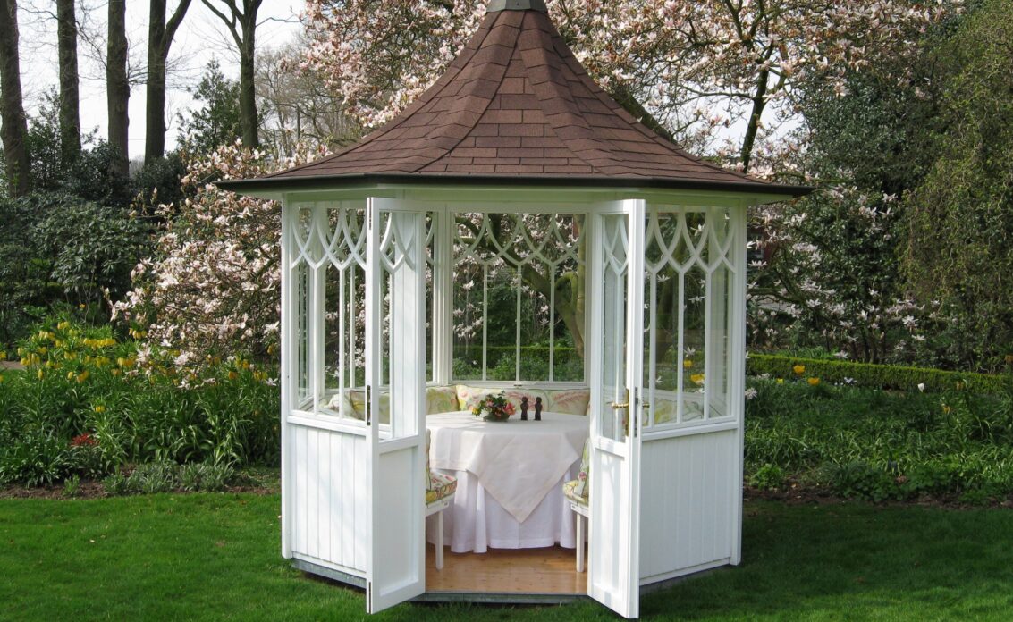Gartenidee mit Gartenpavillon auf der Wiese – Sitzgruppe mit Bänken und Tisch – Blume...