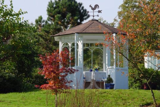 Wetterfeste Gartenpavillon im Garten – Beispiel mit einer Sitzgruppe direkt im Pavillon – Wetterhahn als Gestaltungselement für ländliches Flair