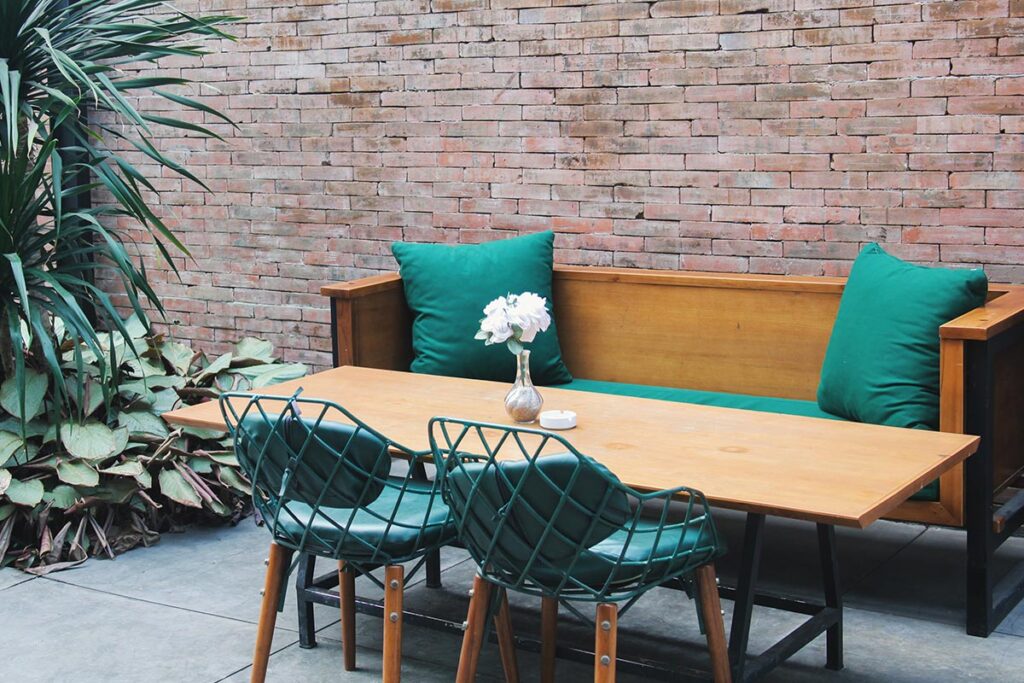 Schöne Terrasse im Innenhof mit ausgiebigen Sitzbereich mit modernen Stühlen, Holztisch und Bank.