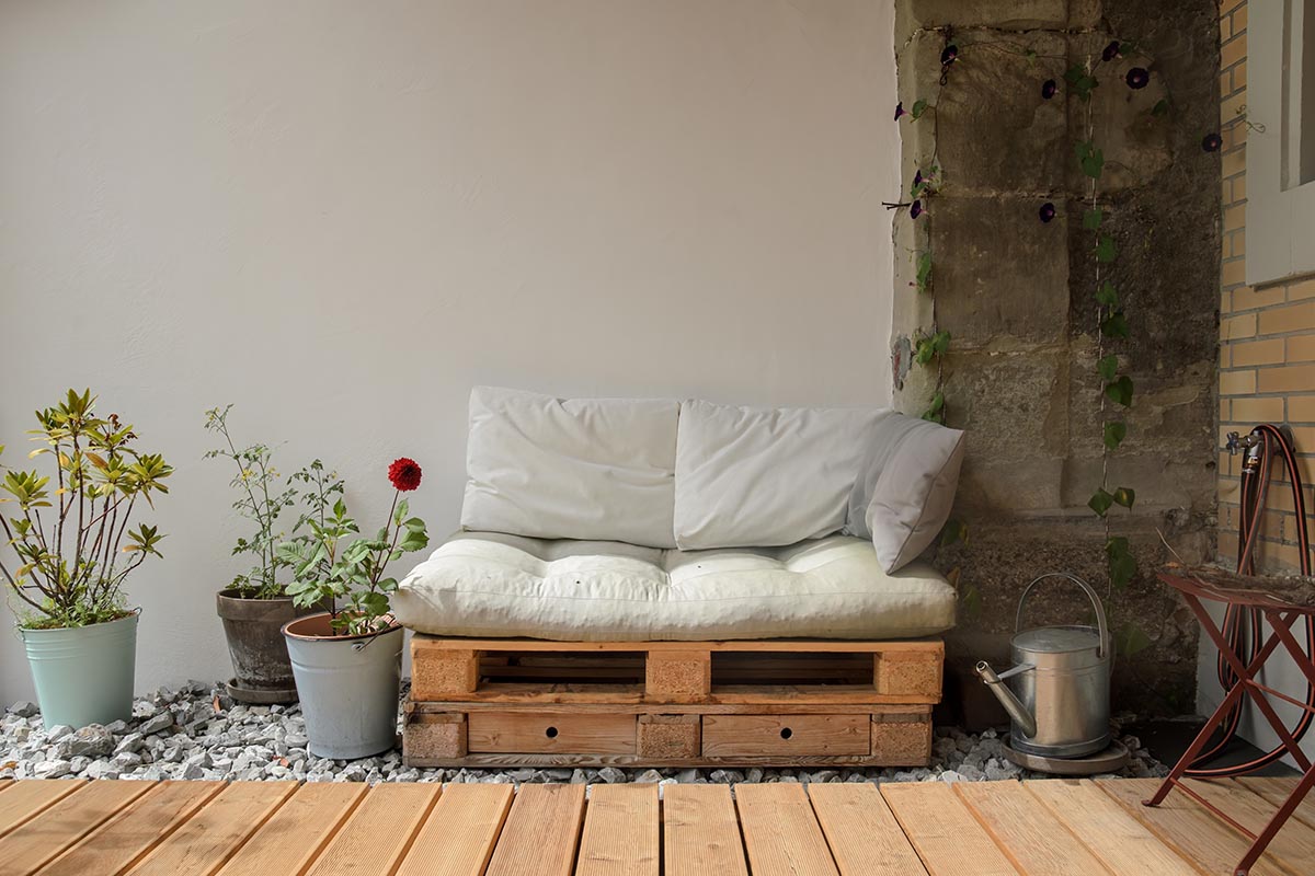 Vintage Terrasse mit DIY Sofa aus Palette und Pflanztöpfen.