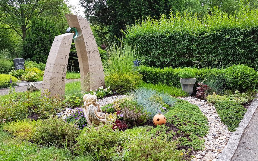Moderne Grabgestaltung mit Kies  Bodendeckern & Gräsern einer Doppelgrabanlage – zweiteiliger Grabstein aus Kalkstein mit Glaselement