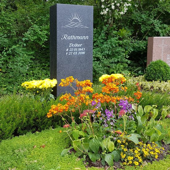 Moderne Grabgestaltung eines Doppelgrabes mit dunkler Granitstele - natürliche Grabeinfassung mit Eibe & Bepflanzung mit einer Mischung aus Bodendeckern und Sommerblumen