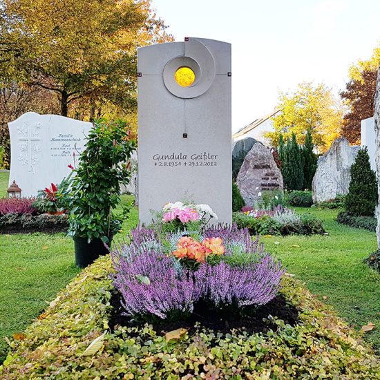 Modernes Einzelgrab aus hellem Kalkstein mit Glaseinsatz & Grabbepflanzung zu Allerheiligen mit Herbststauden & Grablampe
