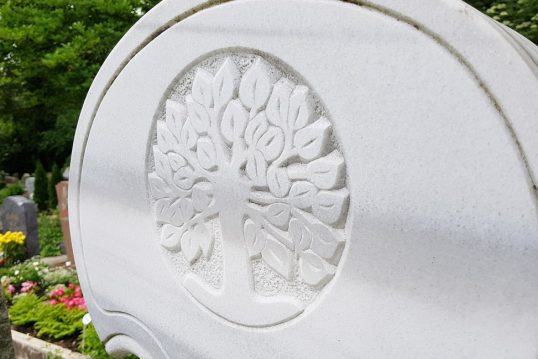 Modernes Doppelgrabmal aus weißem Marmor – geschwungene Form – mit Grabeinfassung und Kies als Gestaltungselement