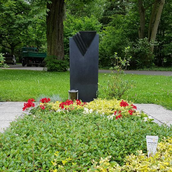 Asymetrische Grabbepflanzung eines modernen Einzelgrabes aus schwarzem Granit mit pflegeleichten Bodendeckern und Sommerblumen