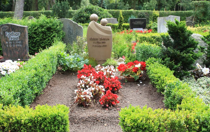 Doppelgrab mit modernem Grabstein aus Quarzit – natürliche Grabumfassung mit Buchsbaum & Bepflanzung mit Sommerblumen