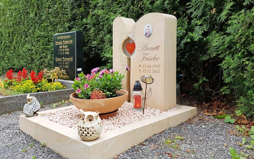 Zweiteiliger Urnengrabstein mit Grabeinfassung aus Sandstein und Glaselement – moderne Grabgestaltung mit Kies & Grabschmuck