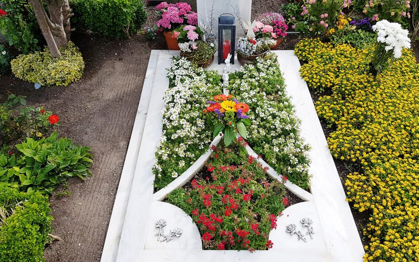 Moderne Grabgestaltung für ein Einzelgrab – aufwendige Grabeinfassung aus Marmor mit Sommerbepflanzung