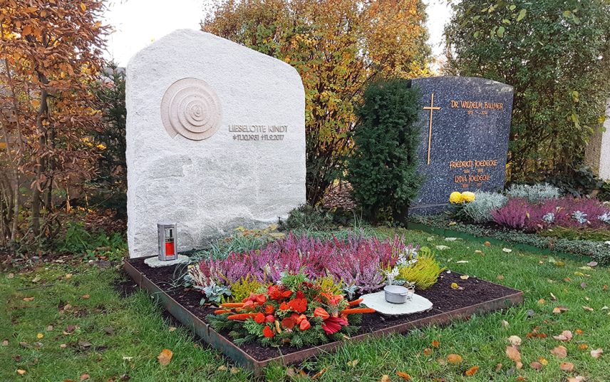 Schönes Gestaltungsbeispiel eines Doppelgrabes mit hellem Grabstein aus Kalkstein zu Allerheiligen – mit Herbstbepflanzung und Grabgesteck